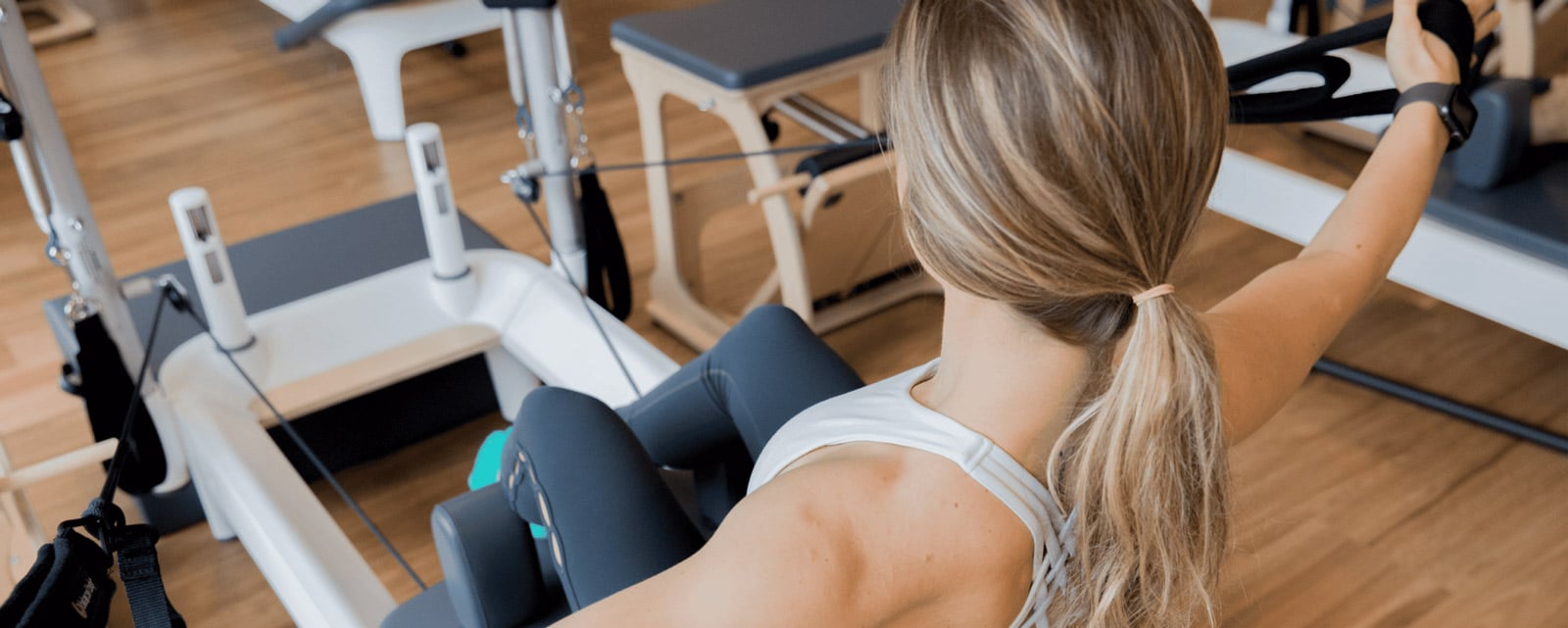 A BODYBAR Pilates student sitting on a legpress machine for the chair reformer workout.