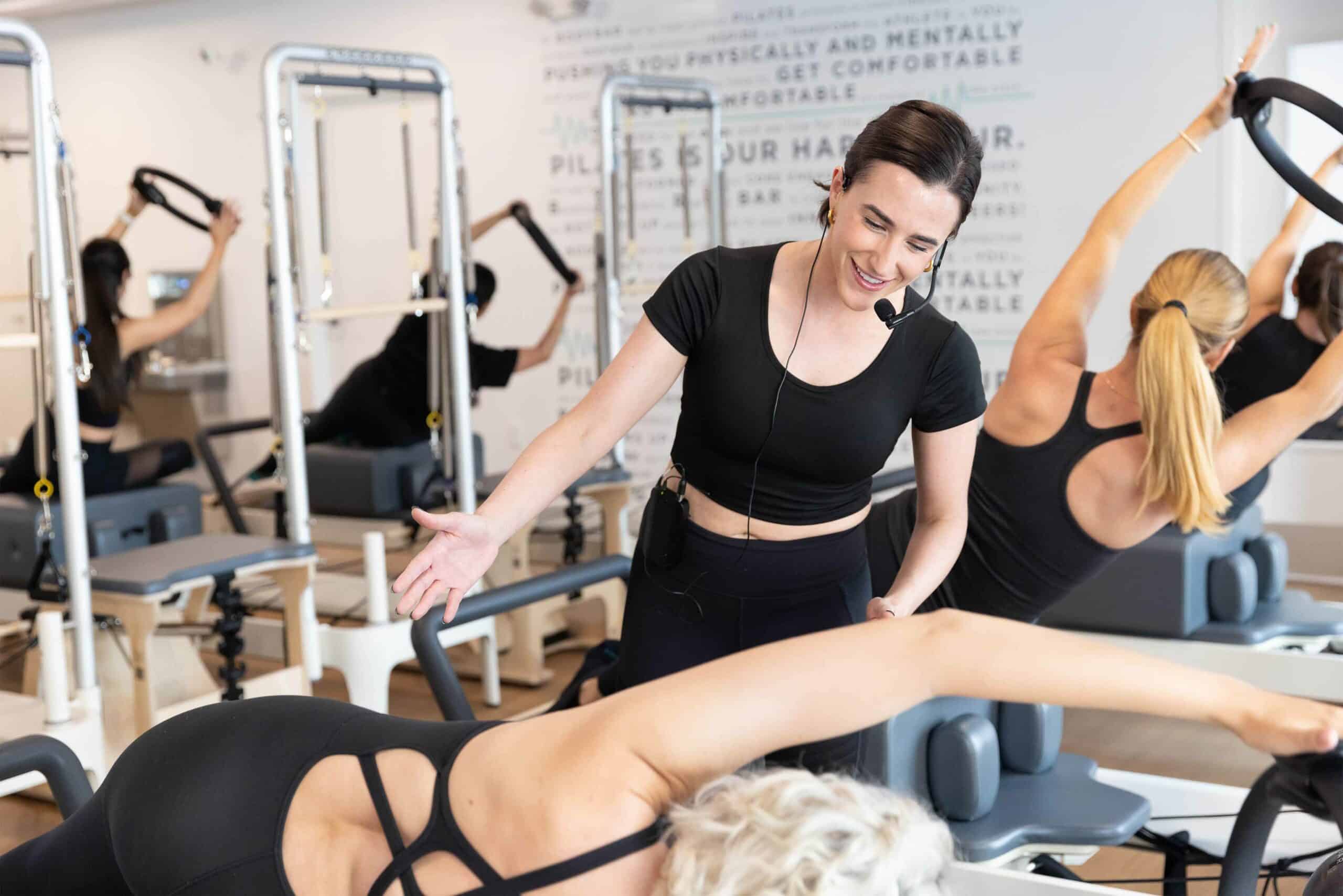 An instructor coaching a client on preforming a Pilates exercise.