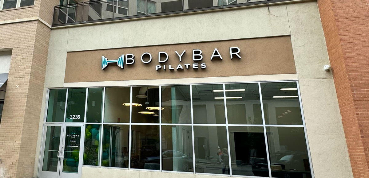 A photograph of the outside of a BODYBAR Pilates studio. Showcasing the sign and logo.