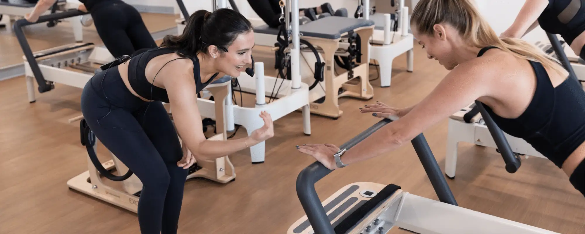 Excited Bodybar instructor providing support to a woman on a reformer