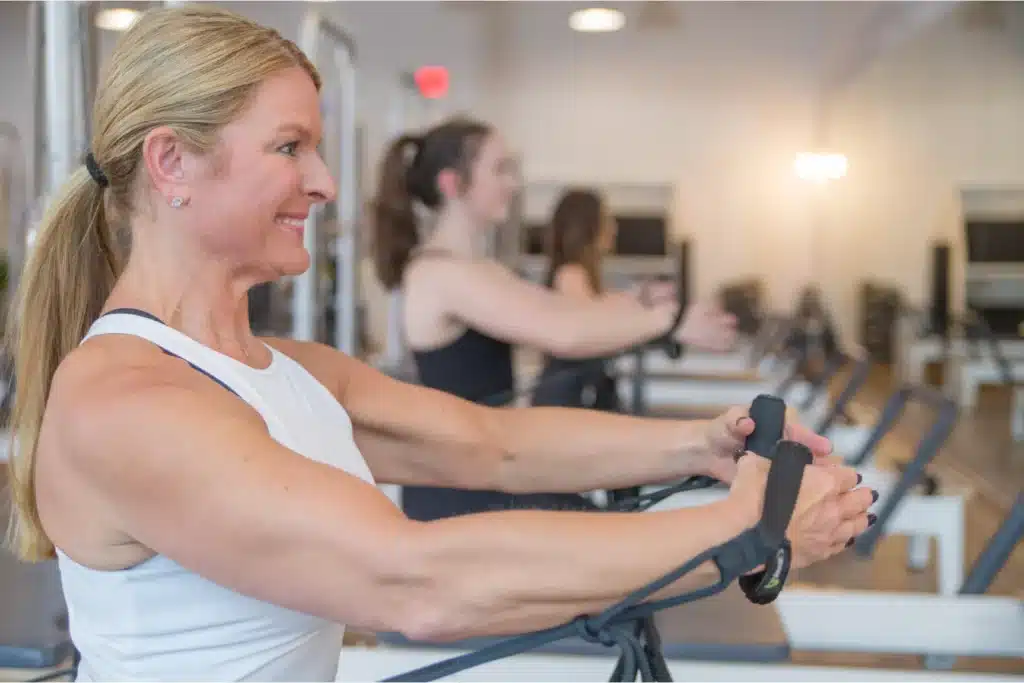 Women exercising with resistance bands in a bright gym, focusing on their workout.