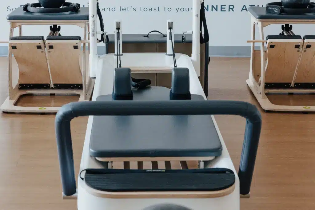 Pilates reformer and equipment in a bright studio with wooden floors and minimal decor.