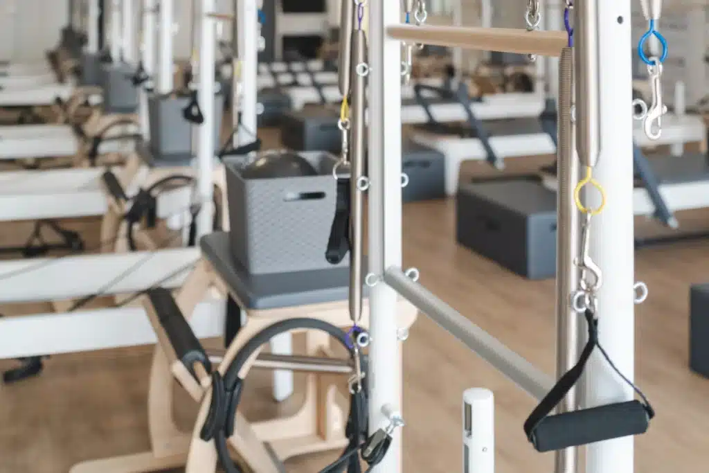 A bright Pilates studio with various Pilates reformer machines and props neatly arranged on a wooden floor.