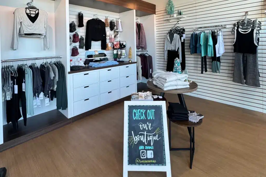 A boutique clothing store displays activewear, with a sign at the entrance promoting their boutique and social media.