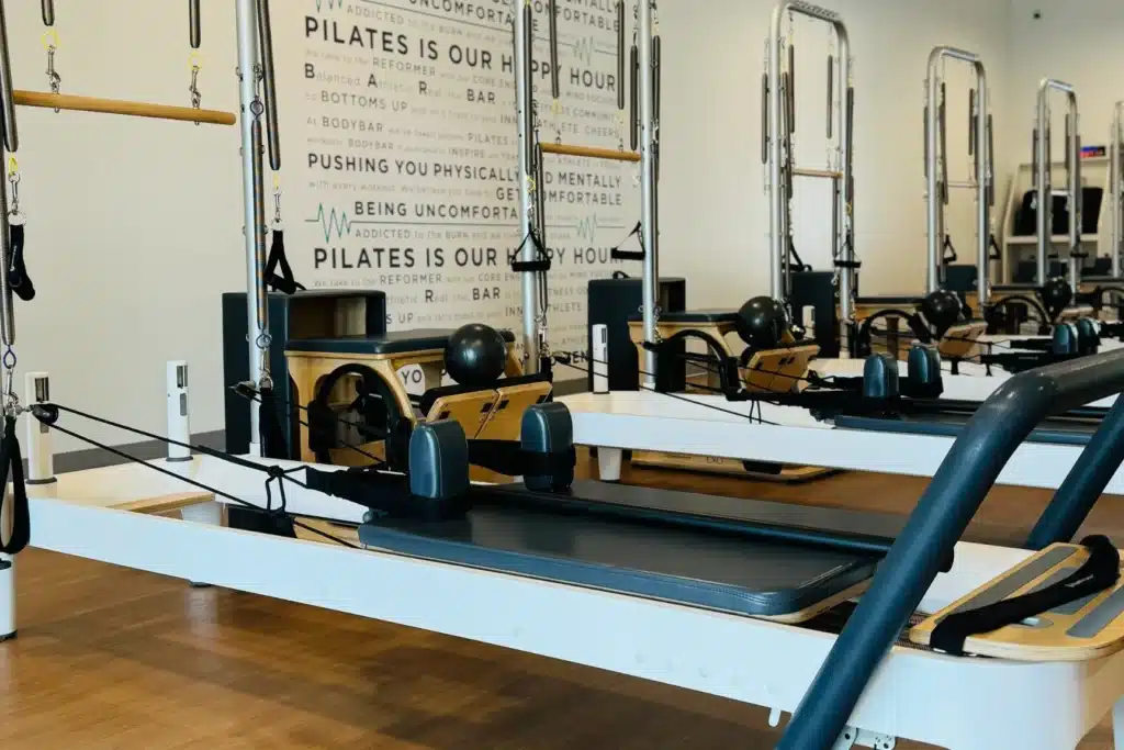 Pilates reformer machines in a bright studio with motivational quotes on the wall in the background.