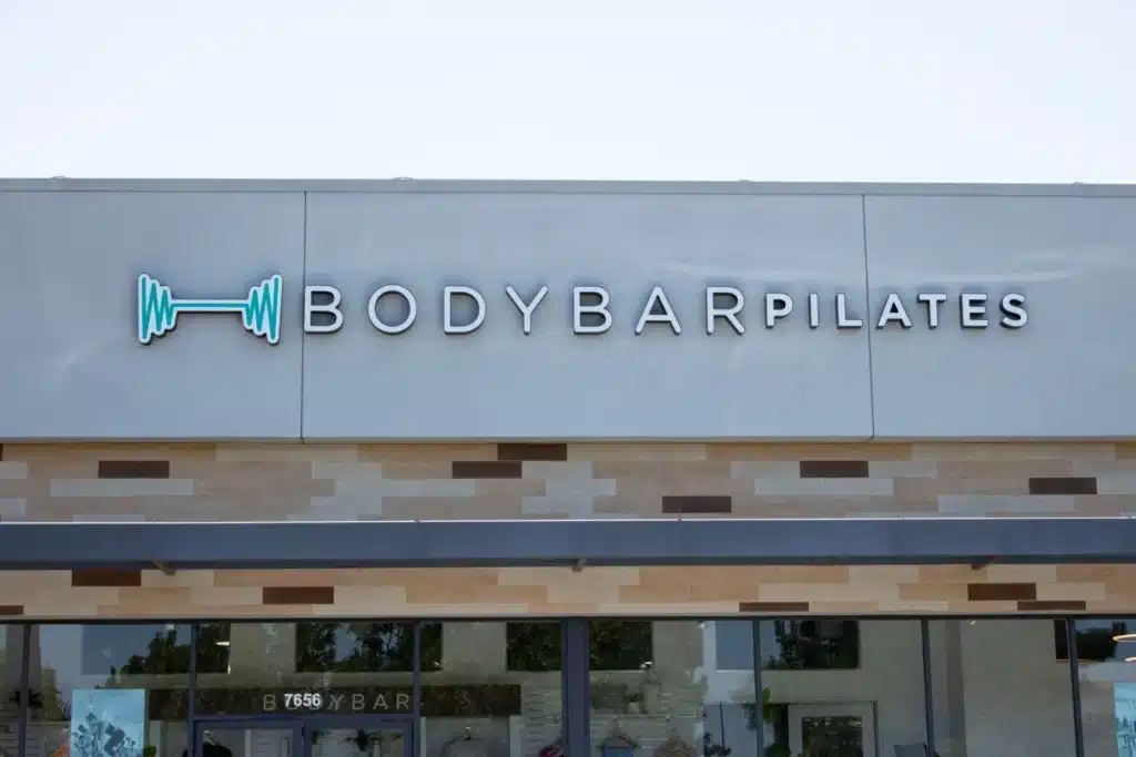 Bodybar Pilates studio exterior with a logo of a barbell and the studio name on a modern building facade.