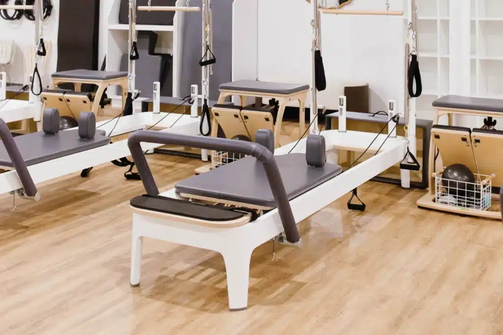 A pilates studio with reformer machines on a wooden floor, ready for a class.