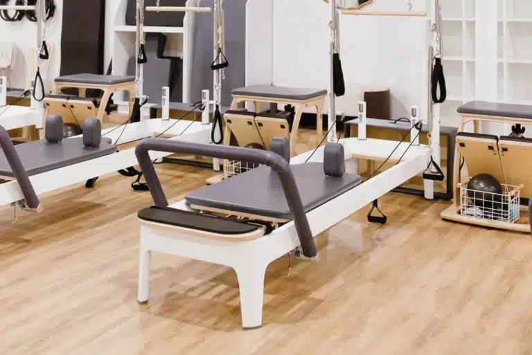 A pilates studio with reformer machines on a wooden floor, ready for a class.