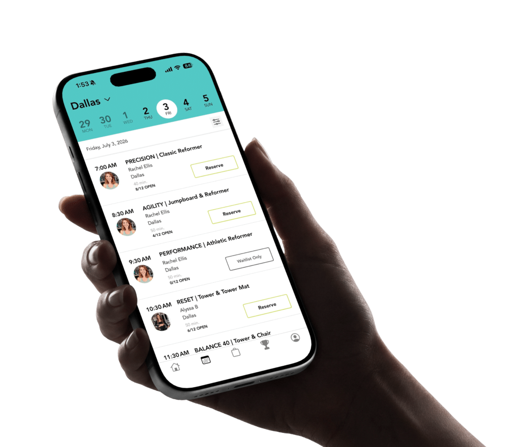 Hand holding a smartphone showing a fitness class schedule app for Dallas with options to reserve classes.